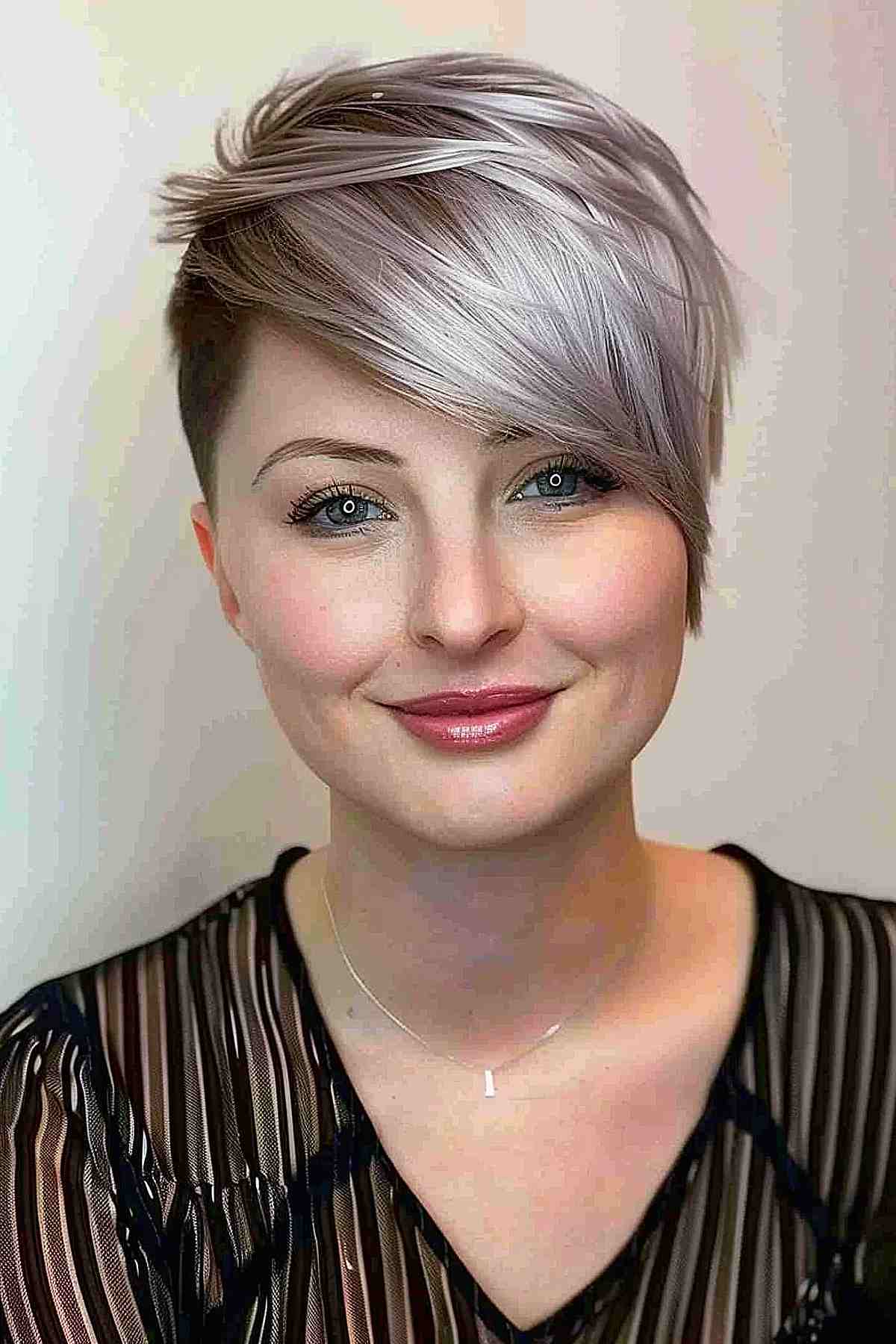 Fine-textured asymmetrical pixie cut with side-swept bangs in a silver-ash blend.